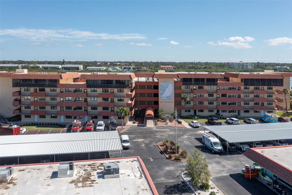 Front view of a multi-story residential building with balconies and a covered parking area.