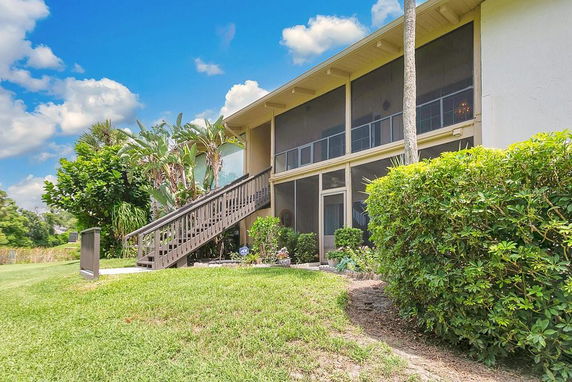 Front view of a two-story house with an external staircase and screened upper balcony.