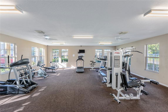 Interior view of a gym with exercise equipment and large windows.