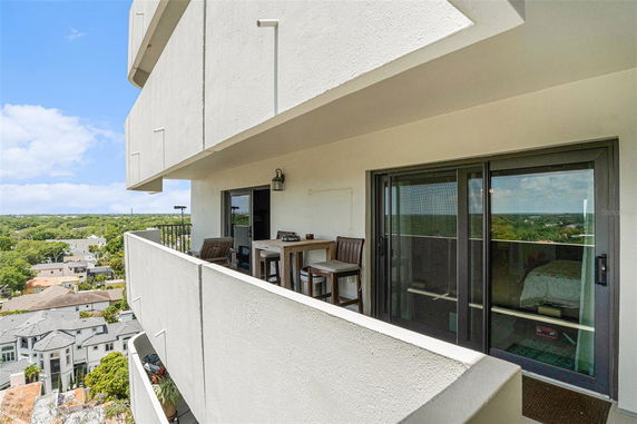 Exterior view from a high-rise balcony with outdoor seating and a view of the surrounding area.