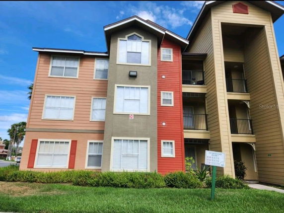 Front view of a three-story apartment building with multiple balconies and windows.