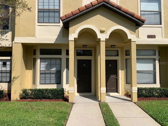 Front view of a townhouse with two entrances and arched porch roofs.