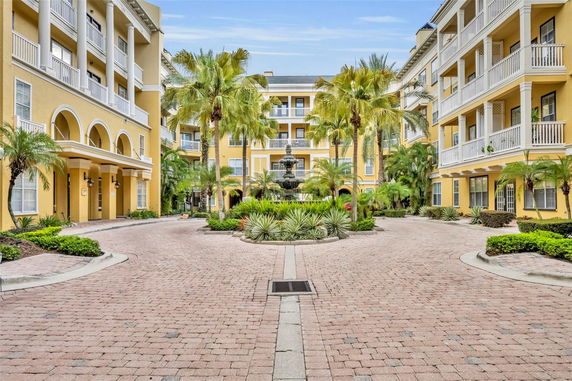 Front view of a multi-story residential building with a fountain and palm trees.