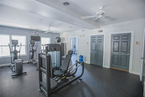 Indoor gym area with exercise equipment and windows.