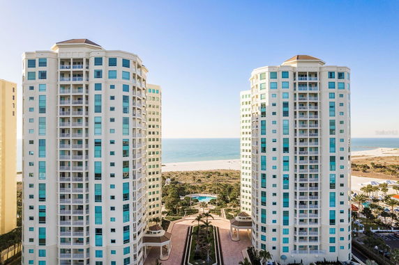 Front view of twin high-rise condominium buildings with balconies and glass windows overlooking a beach.