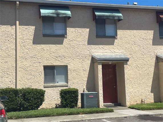 Front view of a two-story building with textured walls and a red door.