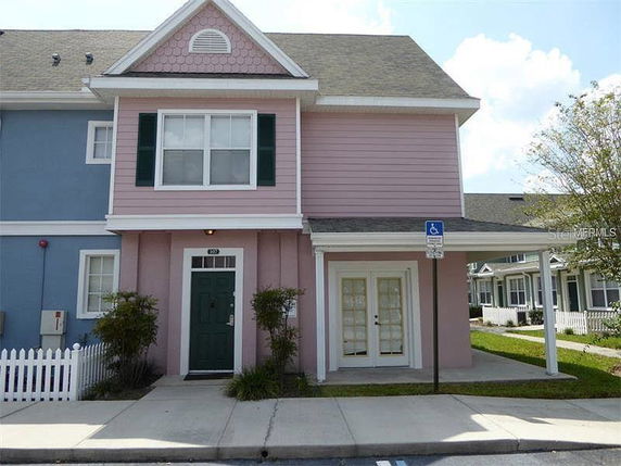 Front view of a two-story house with a pink facade and green door.