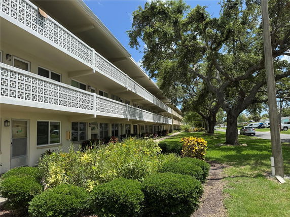 Front view of a multi-story building with decorative railings and a balcony.