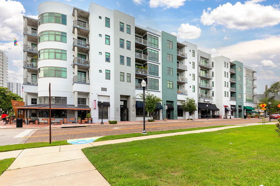 Front view of a multi-story building with retail spaces on the ground floor and balconies on upper floors.