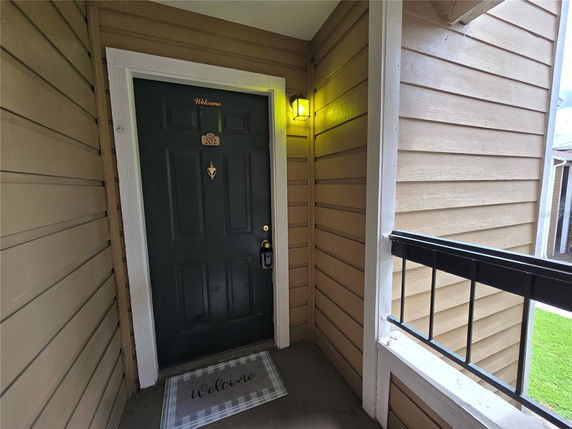 Entrance door view with a welcome mat and adjacent wall.