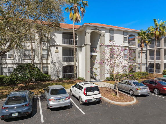 Front view of a multi-story residential building with balconies and a parking area.