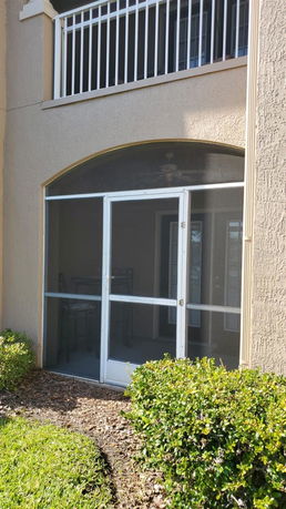 Front view of a building with a screened patio and balcony.
