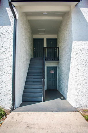 Front view of a building entrance with stairs leading to two doors on the upper level and one door on the ground level.