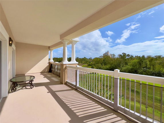 Balcony view with surrounding greenery and distant building.