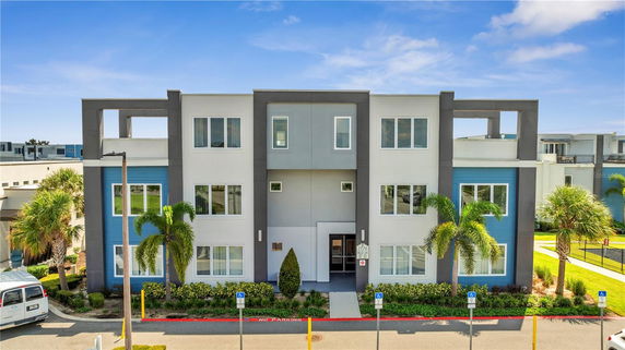 Front view of a modern three-story apartment building with a flat roof and large windows.