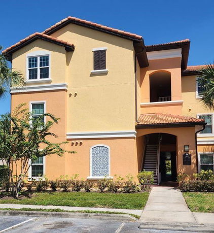 Front view of a multi-story residential building with an arched entrance and outdoor stairway.