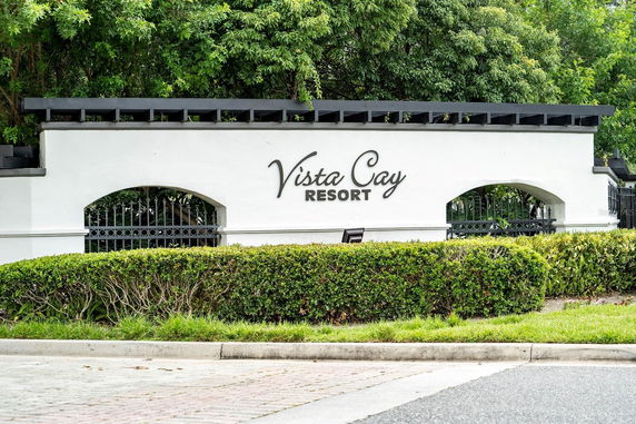 Front view of a resort entrance with a white wall displaying the name 'Vista Cay Resort'.