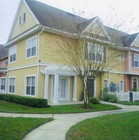 Front view of a two-story yellow house with a gable roof and white trim.