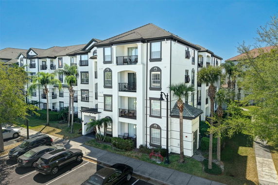 Front view of a multi-story residential building with balconies and a parking area.