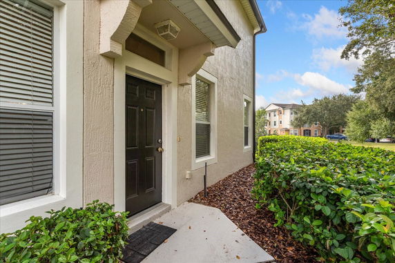 Front view of a house with a black door and windows with shutters.