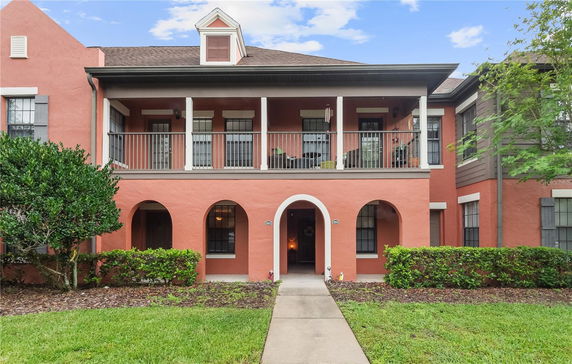 Front view of a two-story house with arched doorways and a balcony.
