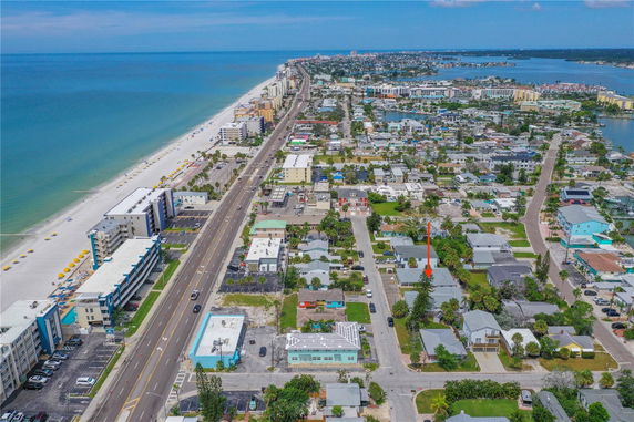 Aerial panoramic view of a coastal neighborhood with a beach, road, and residential area.