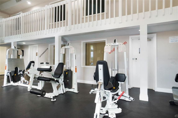 Interior view of a gym area with exercise machines and a balcony.