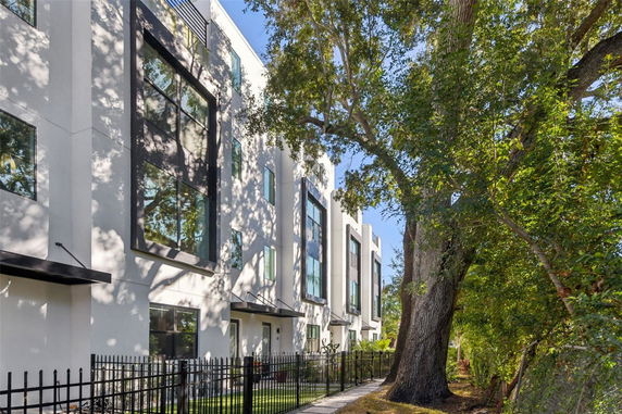 Front view of a modern multi-story building with large windows and a gated entrance.