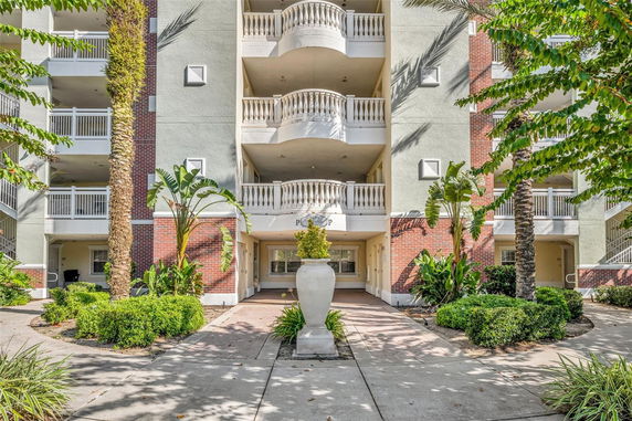 Front view of a multi-story building with balconies and decorative greenery.