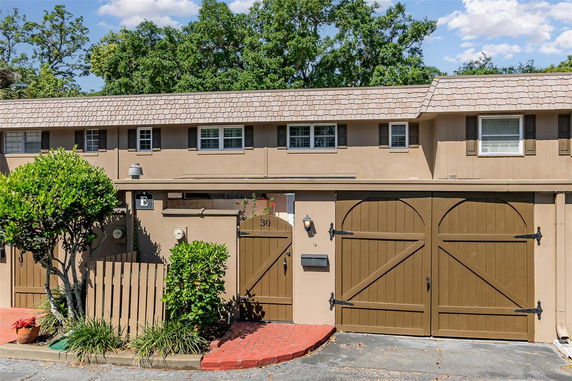 Front view of a two-story house with a double door garage and gated entrance.