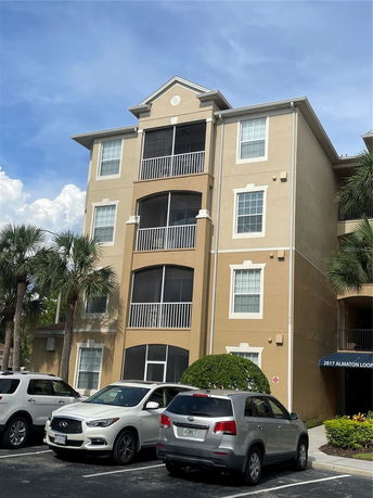 Front view of a multi-story residential building with balconies and parking area.