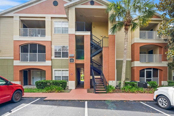 Front view of a multi-story apartment building with balconies and a central staircase.
