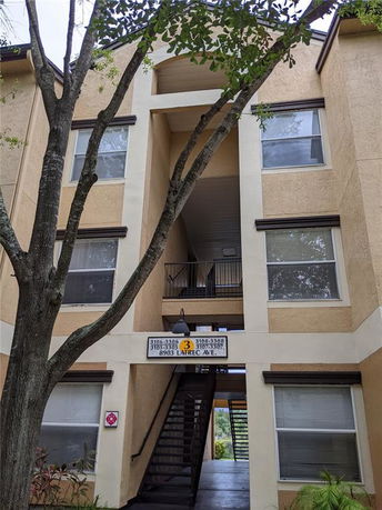 Front view of a multi-story residential building with balconies and staircases.