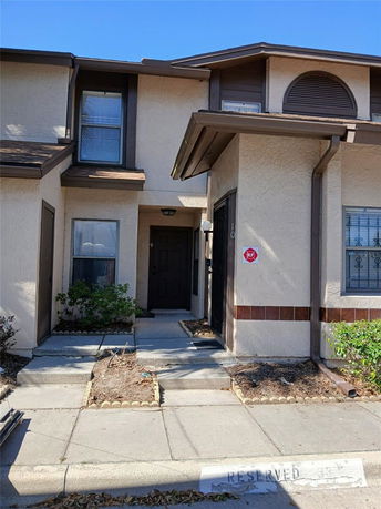 Front view of a two-story townhouse with a dark brown door and small walkway.