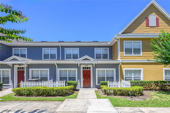 Front view of a two-story townhouse with red doors and white trim.