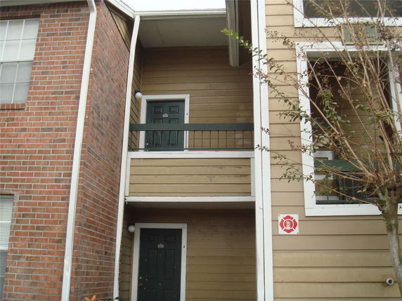 Front view of a multi-story apartment building with balconies and brick siding.