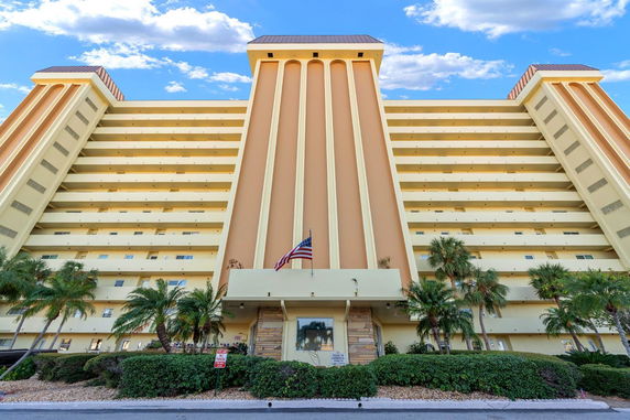 Front view of a multi-story building with a central tall structure and balconies.