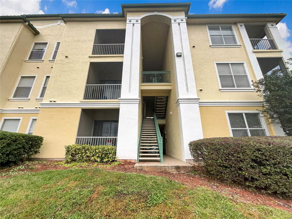 Front view of a multi-story building with balconies and central staircase.