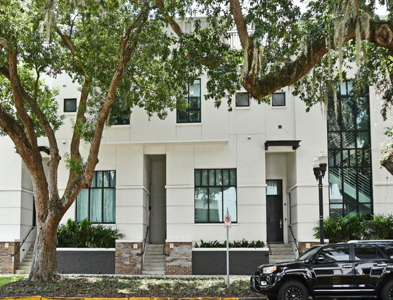 Front view of a modern multi-story building with large windows and steps leading to the entrance.