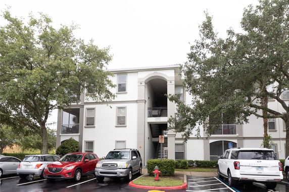 Front view of a multi-story residential building with parking area.