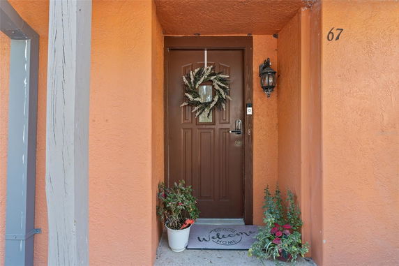 Front entrance of a house with an orange exterior wall and a brown door decorated with a wreath.