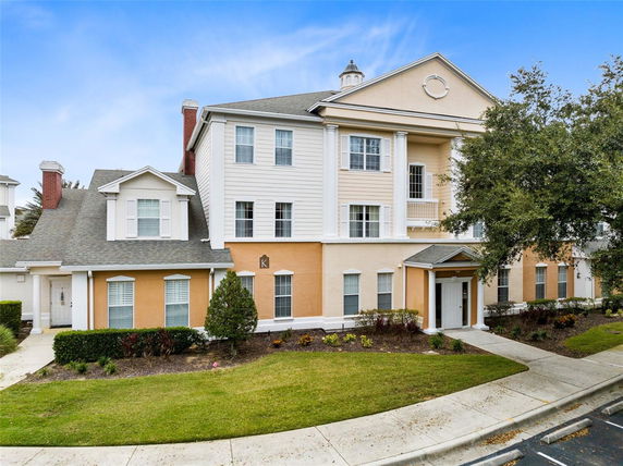 Front view of a multi-story residential building with columns and gabled roof.
