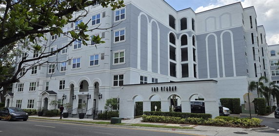 Front view of a multi-story residential building with archways and balconies.