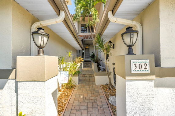 Front view of a modern two-story house with a paved walkway and a decorative lamp.