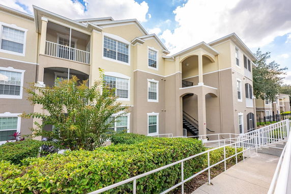 Front view of a multi-story residential building with balconies and a staircase entrance.