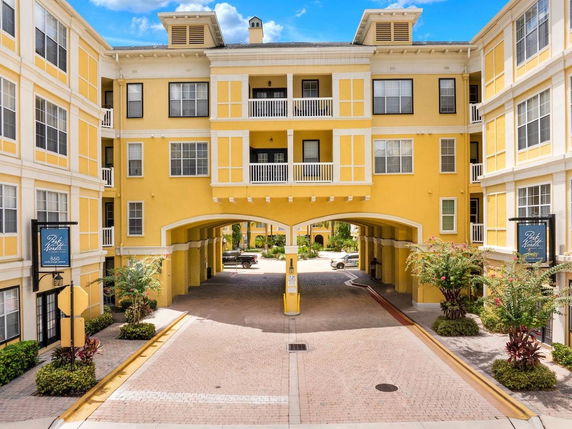 Front view of a yellow multi-story apartment building with an archway entrance.