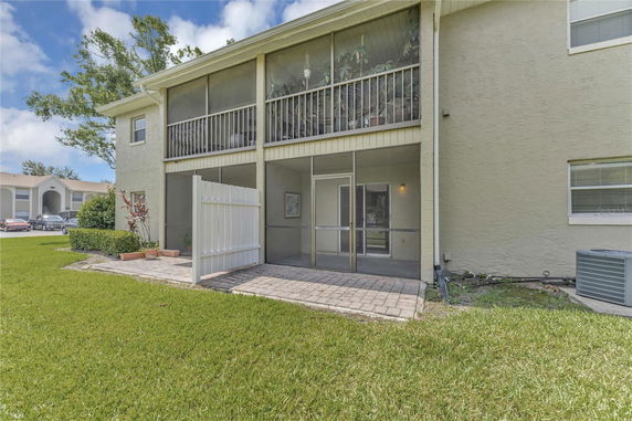 Rear view of a two-story building with a screened patio and balcony.