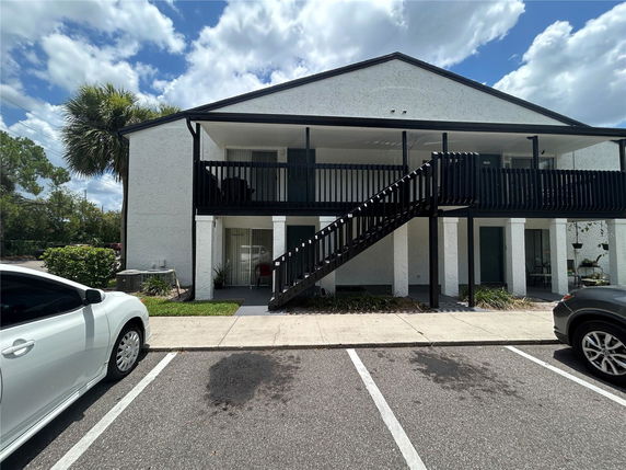 Front view of a two-story building with exterior stairs and a balcony.