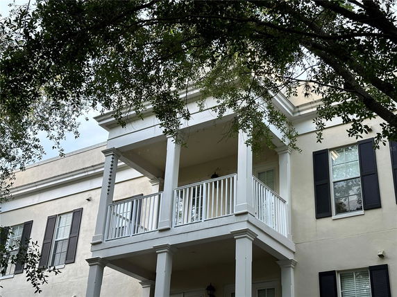 Front view of a house with two-story columns and a balcony.