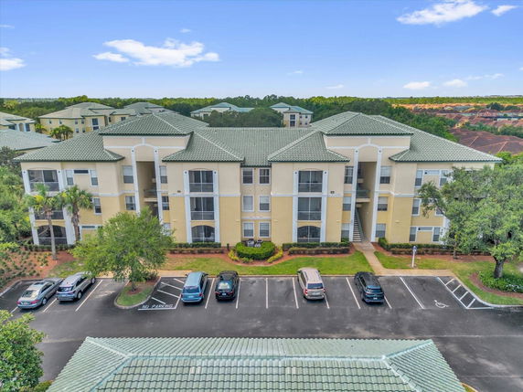 Front view of a three-story apartment building with green roofs and parking area.